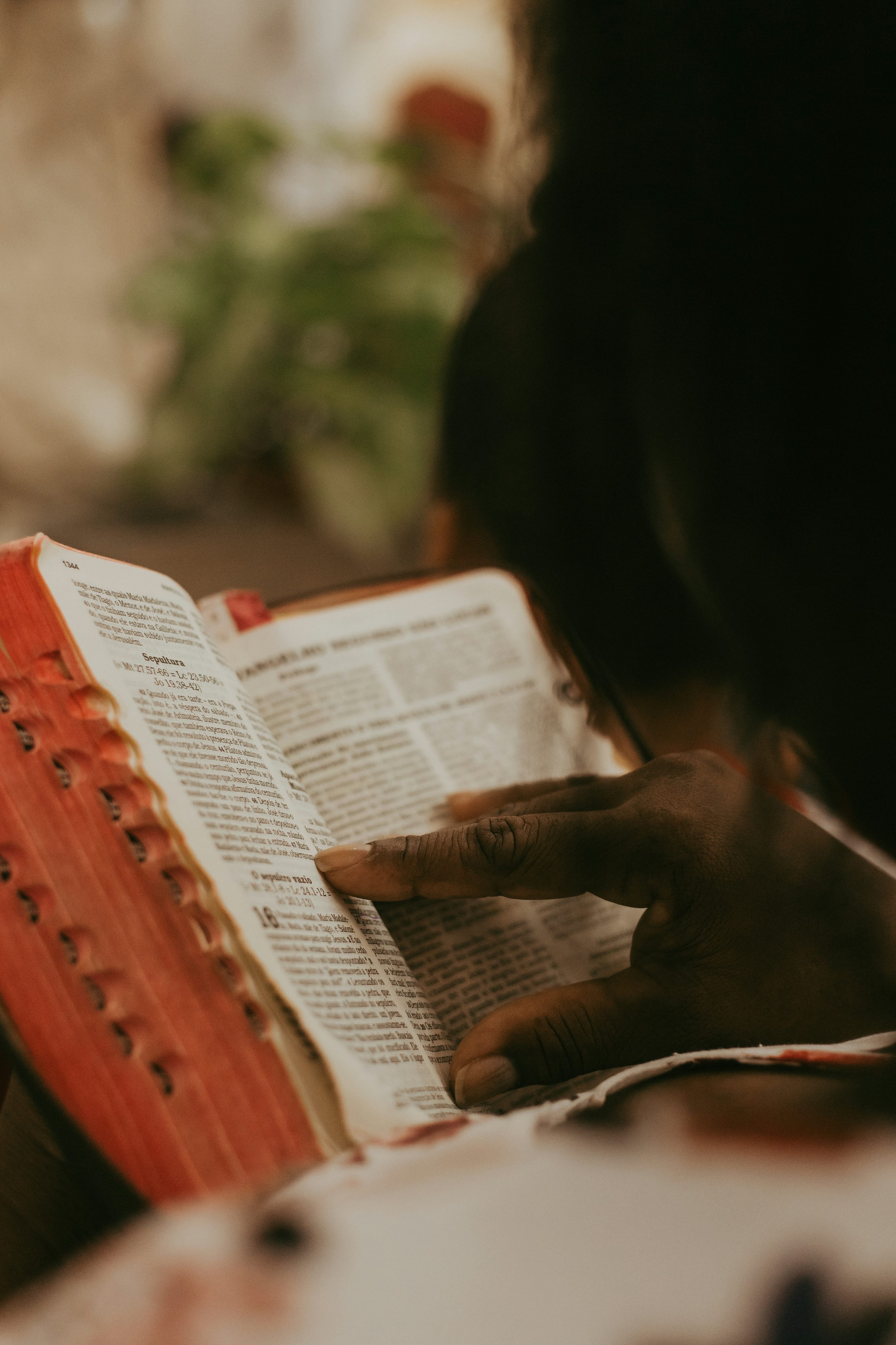 Hands turning the pages of an open Bible in warm light